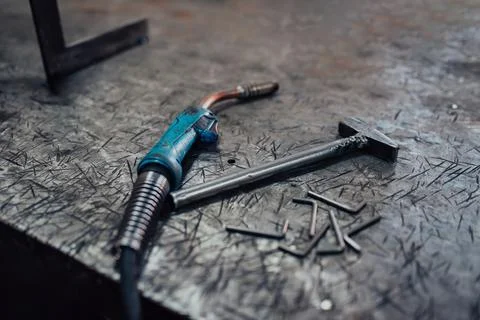 A hammer and a modern welding machine on a steel industrial table Stock Photos