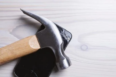 Hammer and smashed phone on the table 스톡 사진