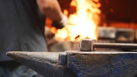 Hammer on anvil and hands of worker on background put wood in furnace with fire. Stock Footage 112859183