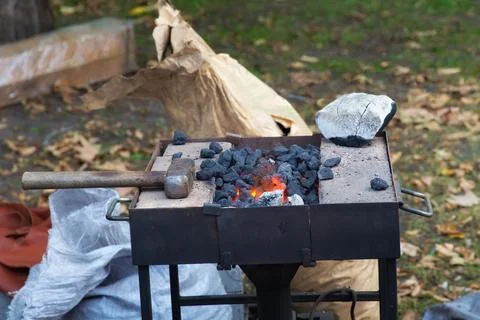 Hammer on the brazier in the street forge workshop. Stock Photos