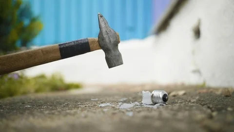 Hammer breaks light bulb on the ground in slow motion 库存影片 112689612