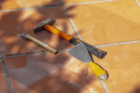 Hammer, chisel and scraper lie on ceramic flooring beside an area undergoing  Stock Photos
