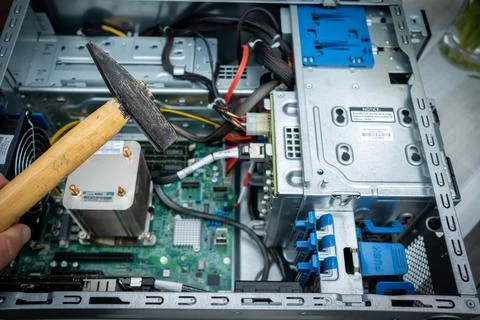 Hammer is held in front of an unscrewed PC Stock Photos