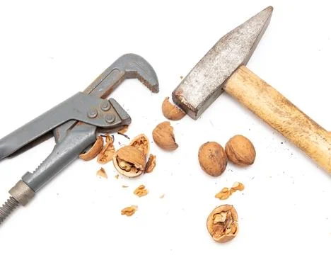 Hammer, nutcracker and walnuts isolated on white background Stock Photos