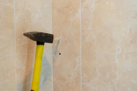 Hammer strikes wall to install hook for hanging items in a home improvement.. Stock Photos