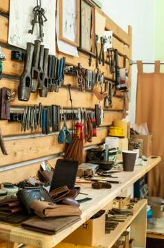 Hammer on table and leather in workshop. Stock Photos