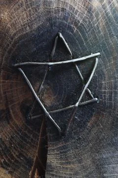 Hammered wire Star of David set into the face of a charred wood block Stock Photos