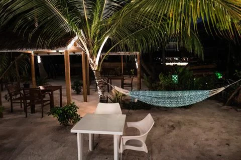 Hammock and dining tables on sandy ground at Dhigurah island resort at night Stock Photos