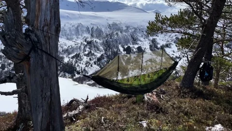 A hammock hangs among the snow-capped mountains Stock Footage 337362047