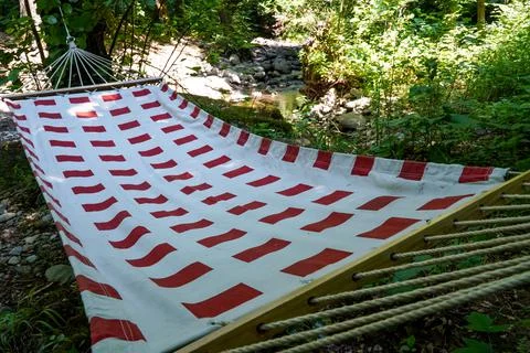 Hammock with red pattern stretched between trees Stock Photos
