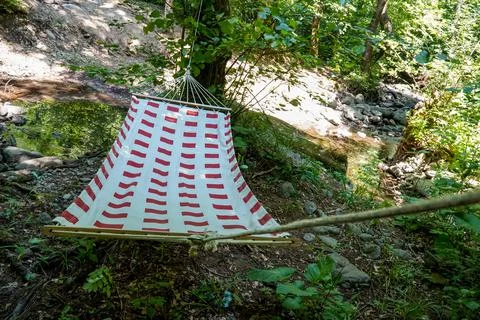 Hammock with red pattern stretched between trees Stock Photos