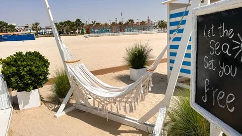 Hammock resting between palm trees on sandy beach with chalkboard menu in Stock Photos