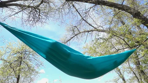 Hammock with a resting man inside swinging in slow motion Video stock 153611939