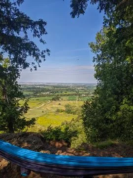 A Hammock  Rests on a Cliff Edge Overlooking Forested Valley &amp; Farm Fields Stock Photos