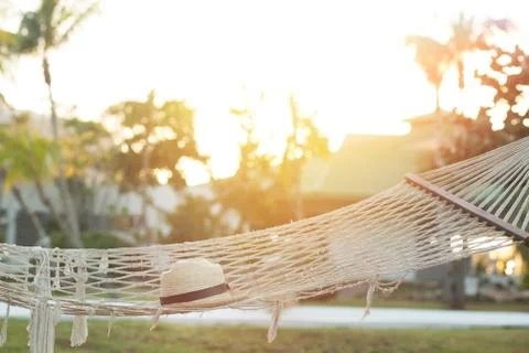 Hammock with straw hat  at sunset Stock Photos