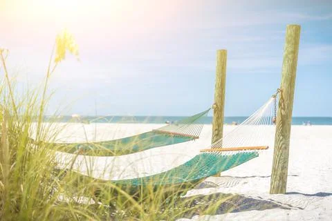 Hammocks on a beautiful wide empty beach with sun shine Stock Photos