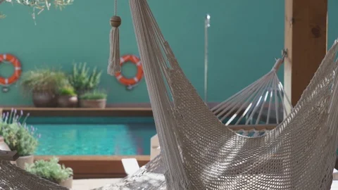 Hammocks swaying in the wind next to a turquoise pool Video stock 100396844