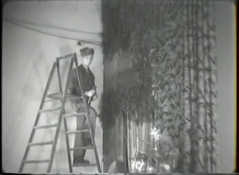HANAU, GERMANY - 1947: Party setup - Worker hangs a sign beside holiday greenery Stock Footage 344488383