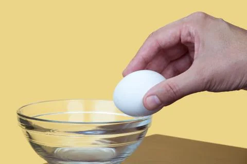 Hand about to crack an egg Stock Photos