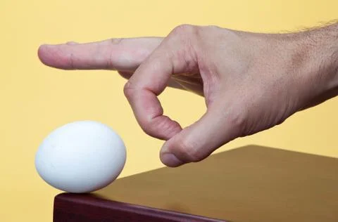 Hand about to flick an egg Stock Photos