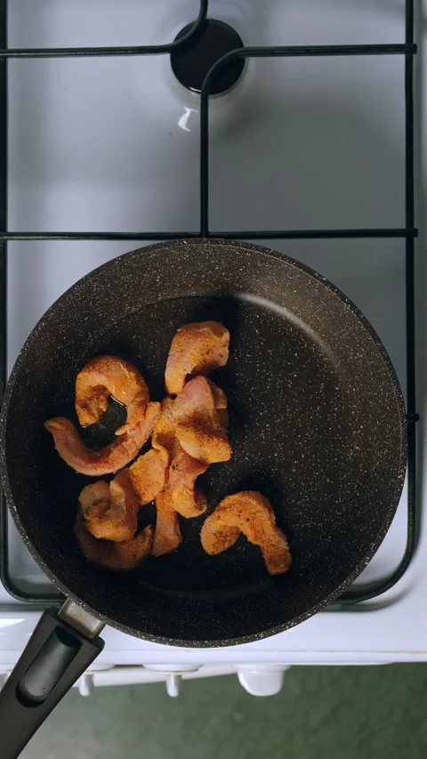 Hand add thinly sliced raw pork strips in frying pan Vídeos de archivo 345481186