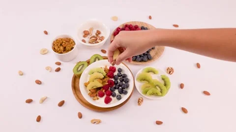 Hand Adding Almonds to Greek Yogurt Bowl with Fresh Fruit Stock Footage 337917794