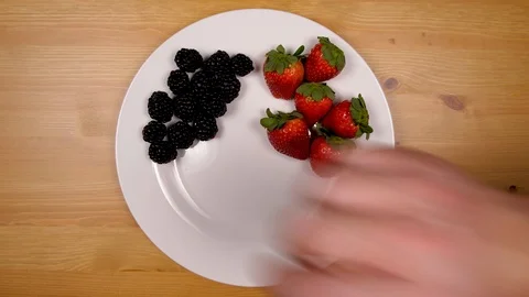 Hand adding and arranging various berries being arranged on plate in 4k. Video stock 86536608