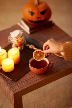 Hand adding dry orange to cup of tea on halloween Stock Photos