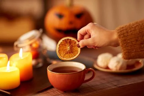 Hand adding dry orange to cup of tea on halloween Stock Photos