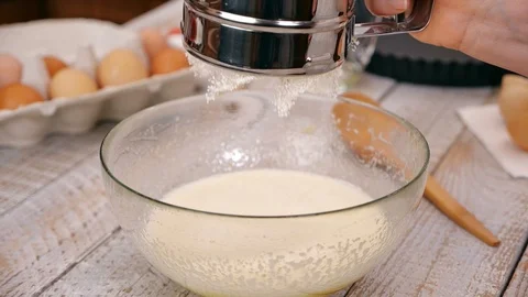 Hand adding flour to cake ingredients in glass bowl - slow motion 動画素材 101863328