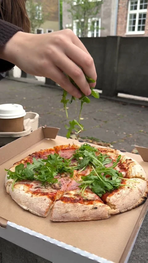 Hand adding fresh arugula leaves to a hot pizza Stock Footage 331772269