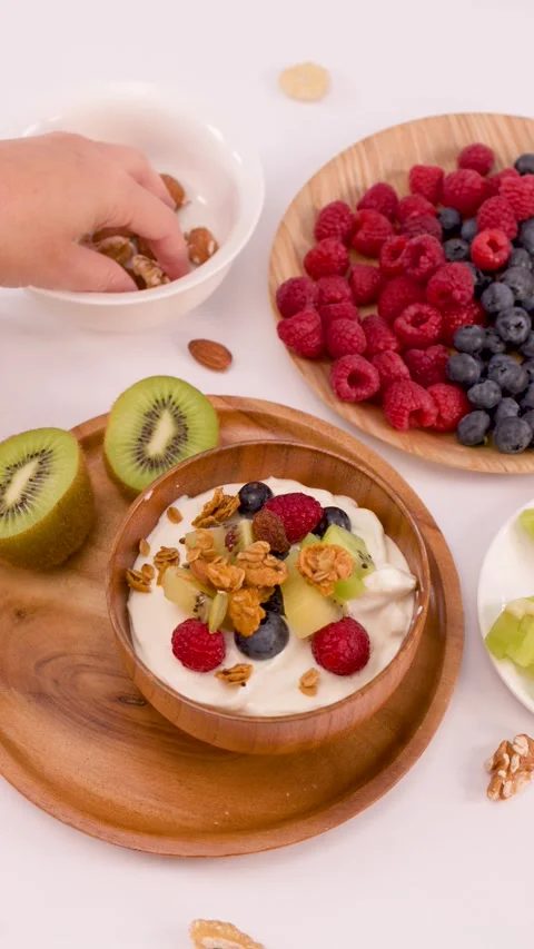 Hand Adding Fresh Nuts to a Healthy Yogurt Breakfast Bowl Stock Footage 337689802