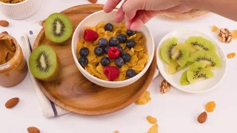 Hand Adding Fresh Raspberries to a Healthy Corn Flake Breakfast Bowl Stock Footage 337691095