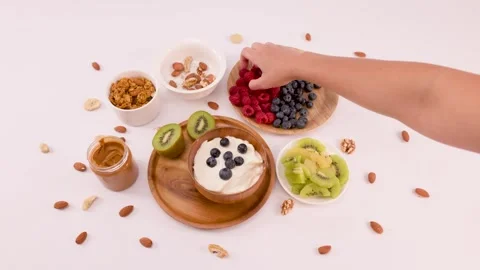 Hand Adding Fresh Raspberries to a Healthy Yogurt Breakfast Bowl Stock Footage 337746704