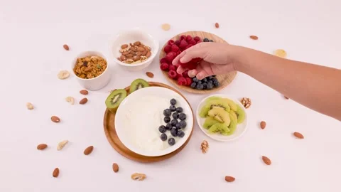 Hand Adding Fresh Raspberries to a Healthy Greek Yogurt Breakfast Bowl Stock Footage 337876889