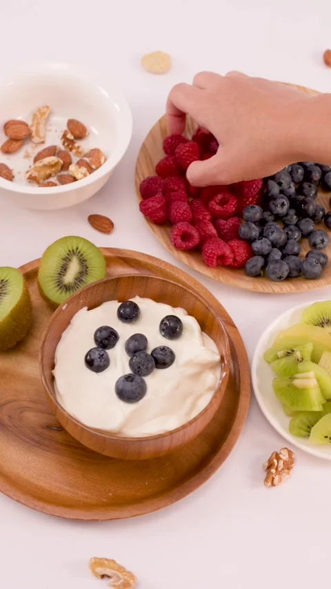 Hand Adding Fresh Raspberries to a Healthy Yogurt Breakfast Bowl Stock Footage 337917886