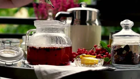 Hand adding ginger, lemon and spices to a pot of tea and mixing on the balcony, Stock-Footage 118831717