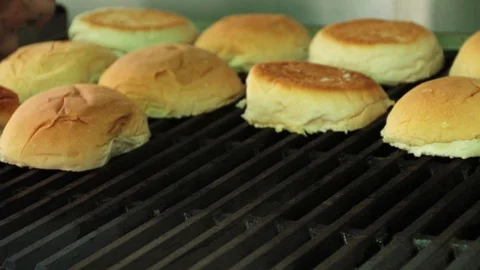 Hand adding hamburger buns on a grill to get toasted Stock Footage 127715894