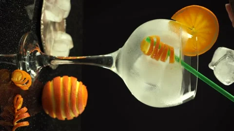 A hand adding ice cubes into gin orange cocktail, 4k vertical video, close up Stock Footage 155648744