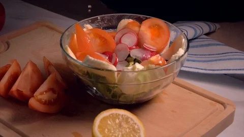 Hand adding lemon in salad with vegetables in glass bowl, slow motion. Stock-Footage 103371286