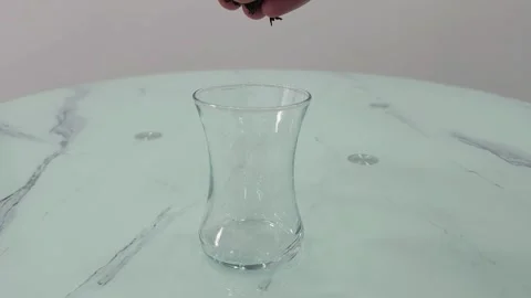Hand adding loose tea leaves into an empty glass. Turkish tea preparation Stock Footage 282610830