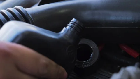 Hand adding oil to engine twisting cap to close Vidéo 107610390