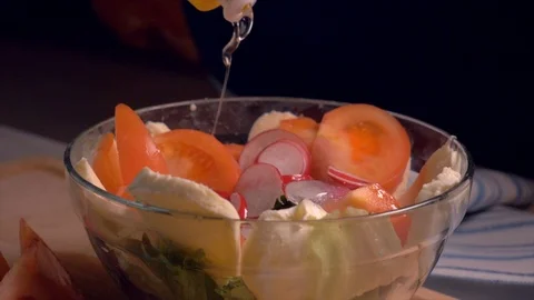 Hand adding oil in salad with vegetables in glass bowl, slow motion. Stock Footage 103368662