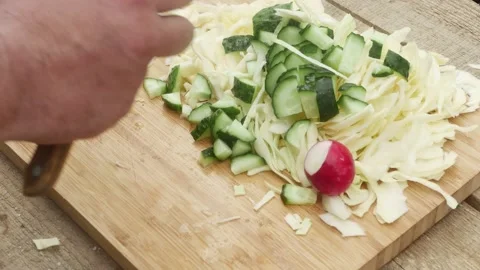 Hand adding radish to cutting board near sliced cabbage and sliced cucumber Vídeos de archivo 195397246