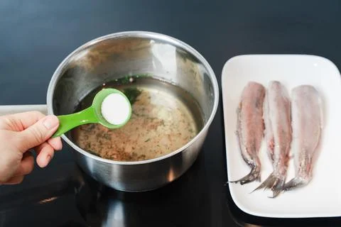 Hand Adding Salt To Brine For Herring Preparation Stock Photos