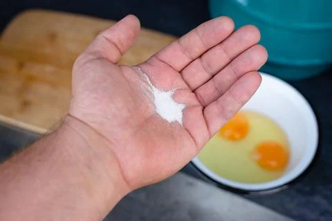 Hand adding salt to eggs Stock Photos