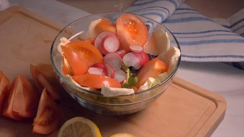 Hand adding salt in salad with vegetables in glass bowl, slow motion. Stock Footage 103368293
