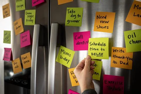 Hand Adding Schedule Time to Relax Sticky Note Memo to Fridge Door Full of Co Foto stock