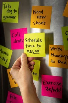Hand Adding Schedule Time to Relax Sticky Note Memo to Fridge Door Full of Co Foto stock
