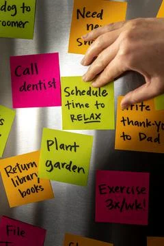 Hand Adding Schedule Time to Relax Sticky Note Memo to Fridge Door Full of Co 写真素材